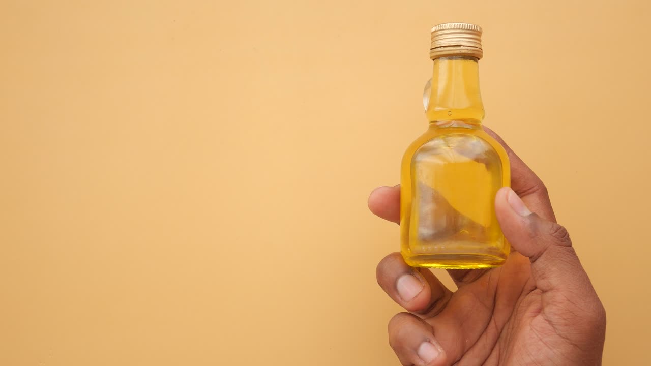 Small Glass Bottle of Oil in Hand