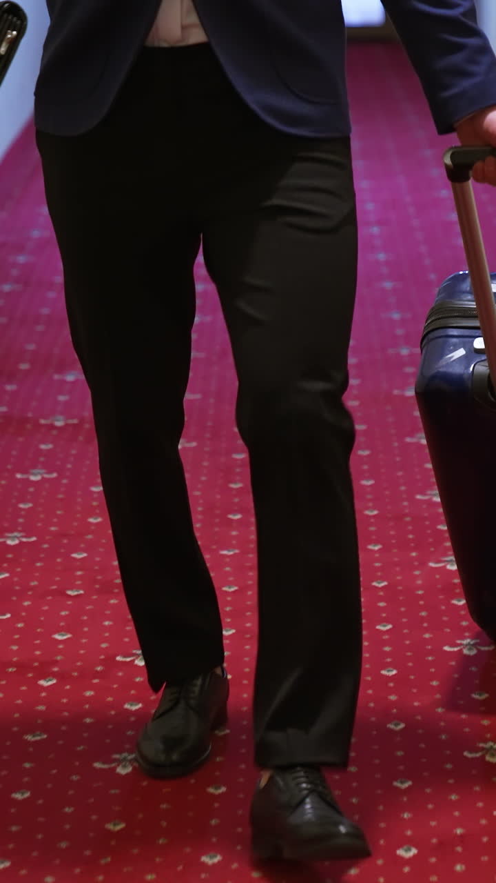 Businessman in hotel corridor with suitcase. Male businessman walking with luggage in hotel corridor. Vertical video
