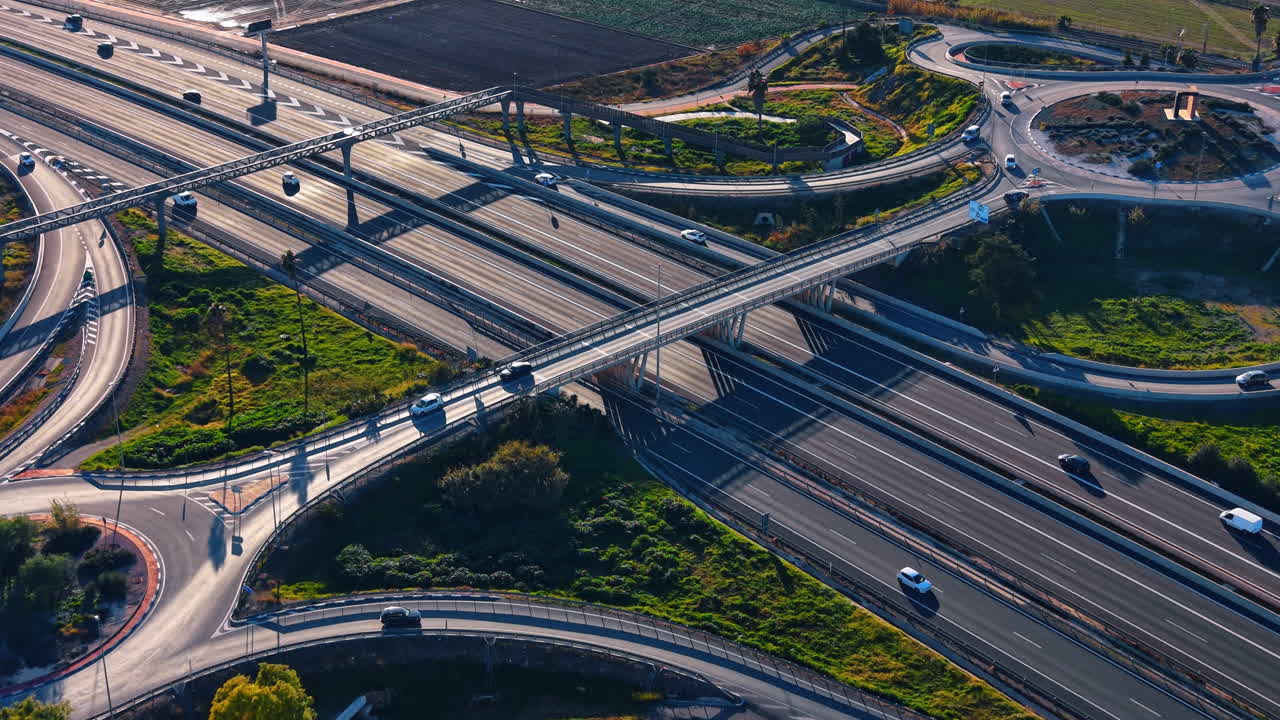 Aerial perspective of complex highway junction and roundabouts. Low angle sunlight over multi-level road intersection with ramps, bridges and long shadows