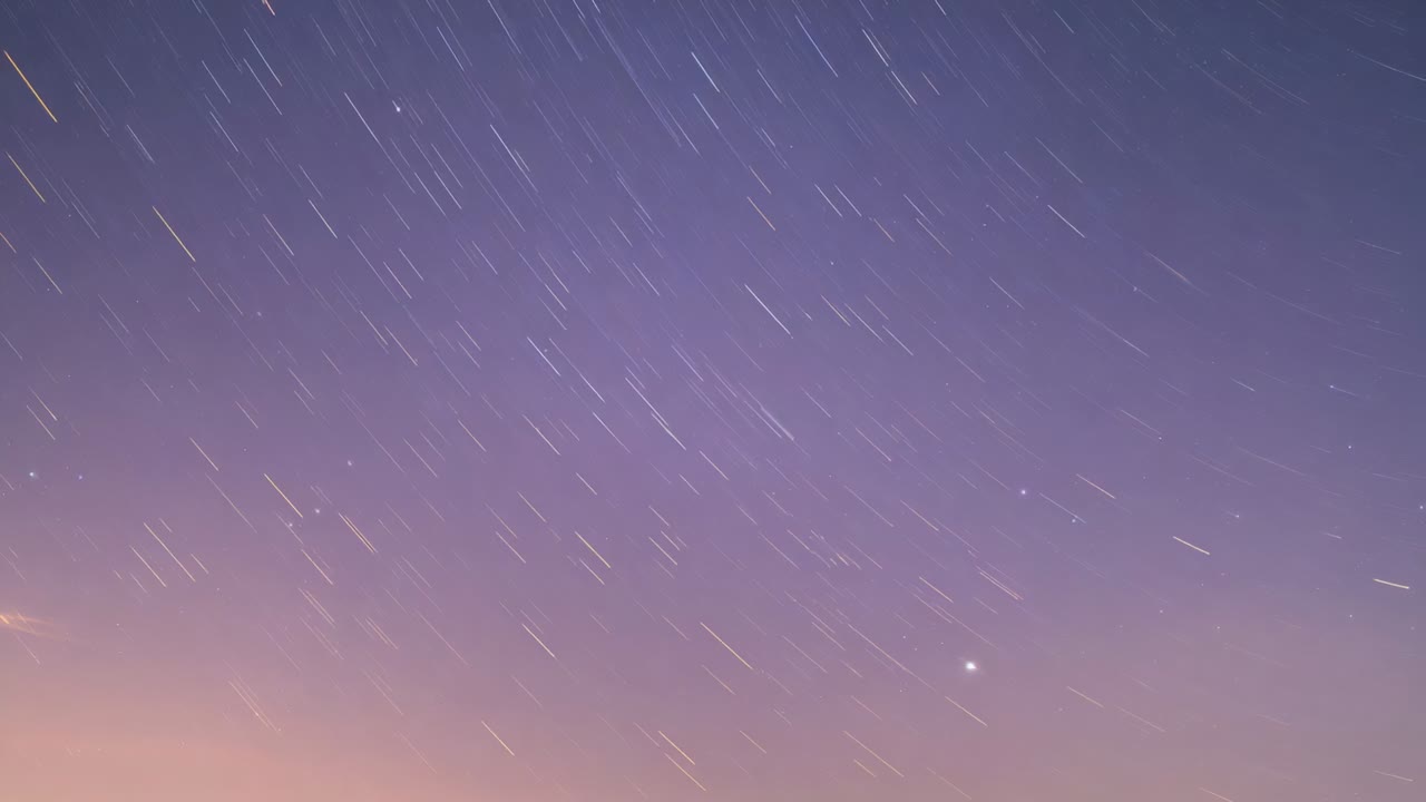 Entering frame from upper-left, meteor burning during entry across twilight sky, with star trails
