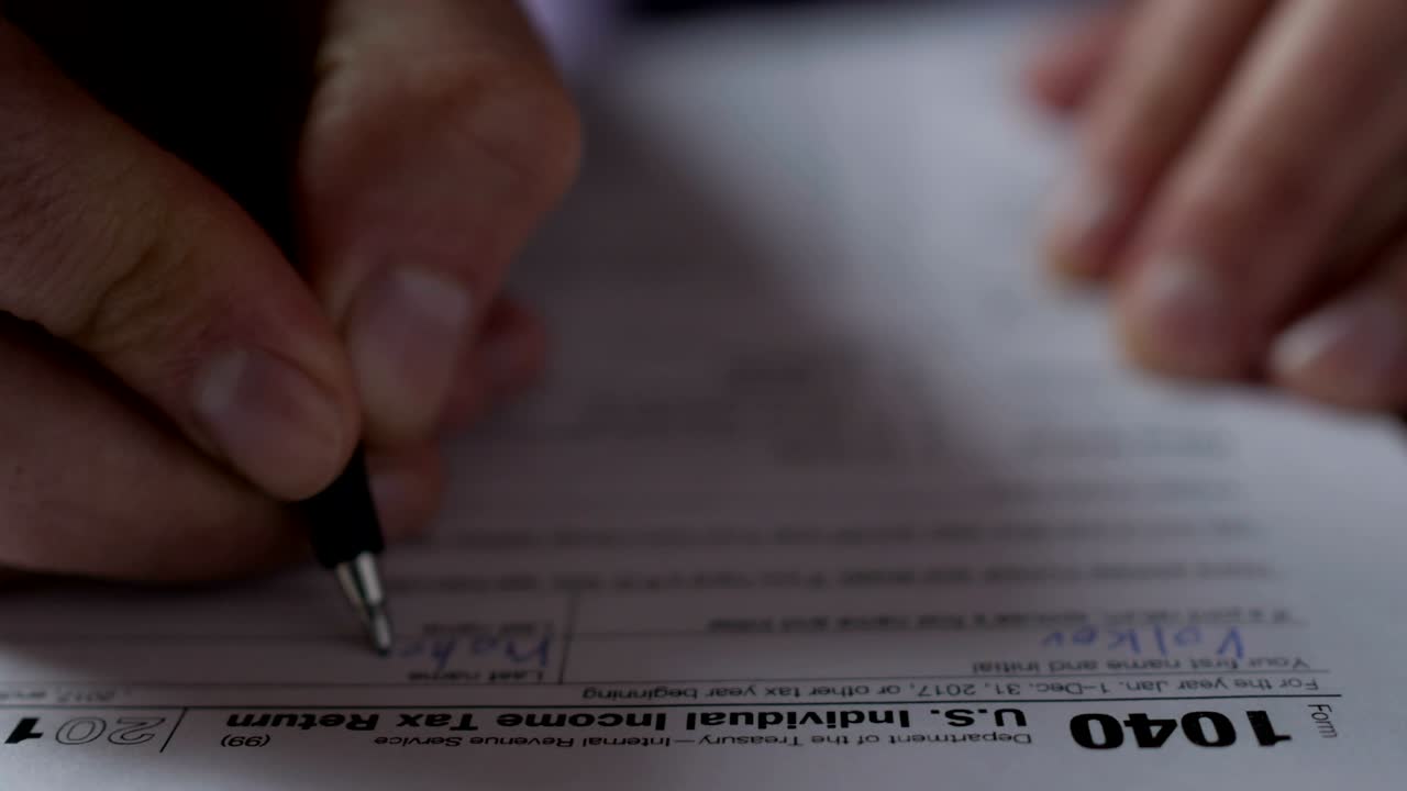 hombre llenando el formulario de impuestos de los estados unidos. formulario de impuestos del despacho de ingresos empresariales. concepto de relleno a mano. primer plano. hombre comprobando la caja de estado de presentación en el formulario 1040 de declaraciones de impuestos de ingresos individuales de los ee.