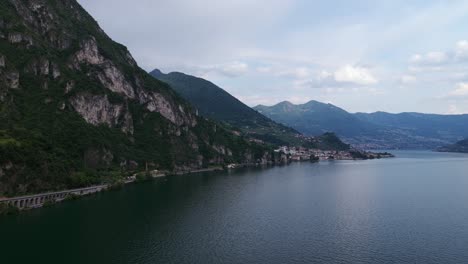 marone town nestled by lake iseo, italy, coastal road, viaduct, mountains, and calm water, lombardy, travel destination, copy space. aerial drone panoramic view
