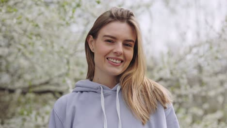 smiling woman in a lavender hoodie in a spring blossom garden