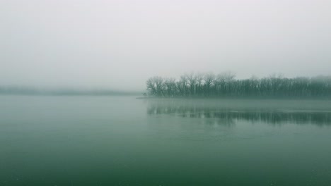 a foggy landscape with still water and distant trees creates a calm, peaceful atmosphere