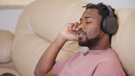 man listening to music on headphones on a couch.