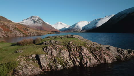 flying to small island in dark lake surrounded by snow capped mountains at wasdale lake district uk