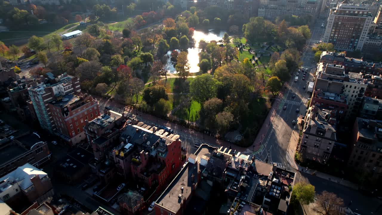 Sorvolo di Drone su Appartamenti del Centro verso il Giardino Pubblico Boston Common, Luce Solare Riflessa sulla Superficie del Lago