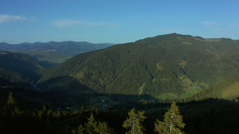 Vista-Aérea-Del-Pueblo-Del-Valle-De-Montaña-Con-Encantadores-Picos-Rocosos-Verdes-Y-Cielo-Azul