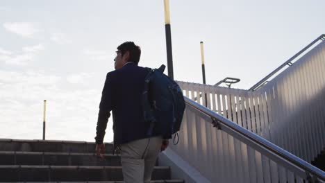 asian man with backpack climbing up the stairs at corporate park