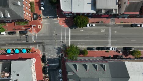 Straight-down-truck-shot-of-city-neighborhood-with-brick-sidewalks-and-tall-residential-buildings