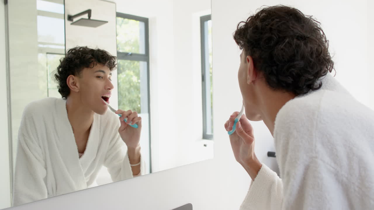 Brushing teeth, person in bathrobe looking in mirror in bright bathroom