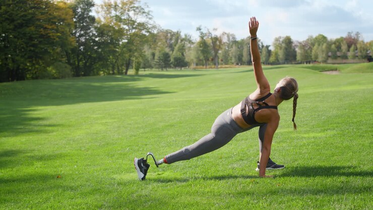 Disabled athlete stretching body in park. Girl practicing yoga in green area