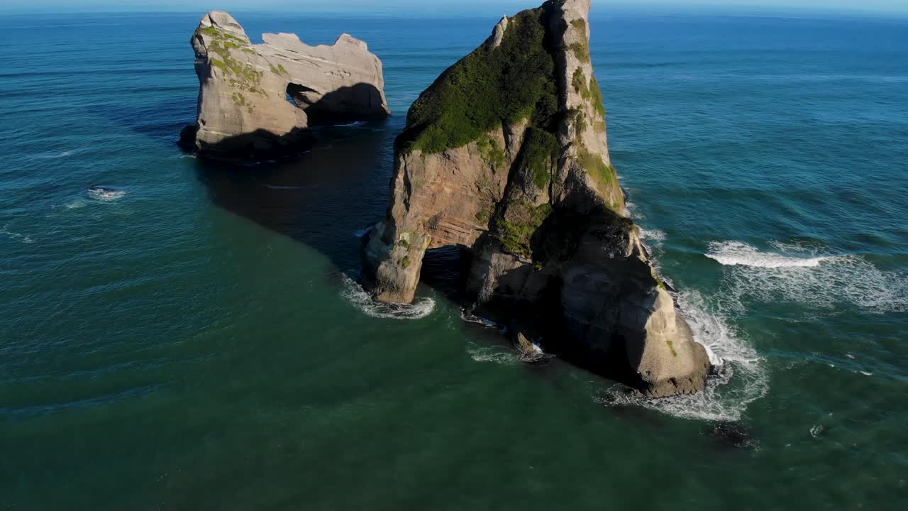 Zonlicht op rotsformaties voor de kust met opspattende golven.