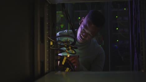 African-american-male-computer-technician-using-smartphone-working-in-business-server-room