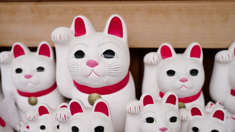 hundreds of maneki-neko cats on wooden shelves at a japanese temple