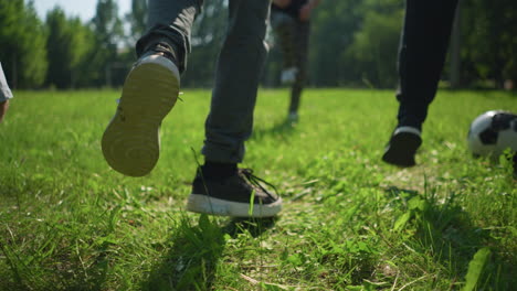 close up leg view of people jumping on a grassy field, with a blurred goal post in the background