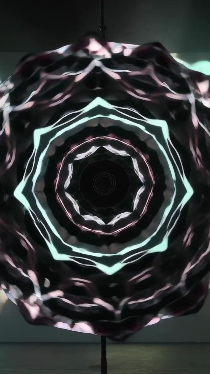 Video verticale: Luce che avvia un disco caleidoscopico su un'asta che ruota in una stanza, creando motivi in movimento