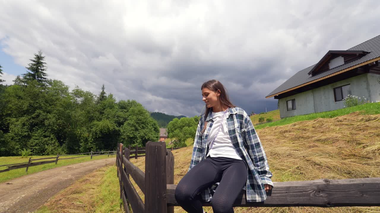 Donna che si rilassa vicino a una staccionata di legno in un villaggio di montagna