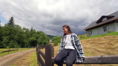 mujer relajándose cerca de una valla de madera en un pueblo de montaña
