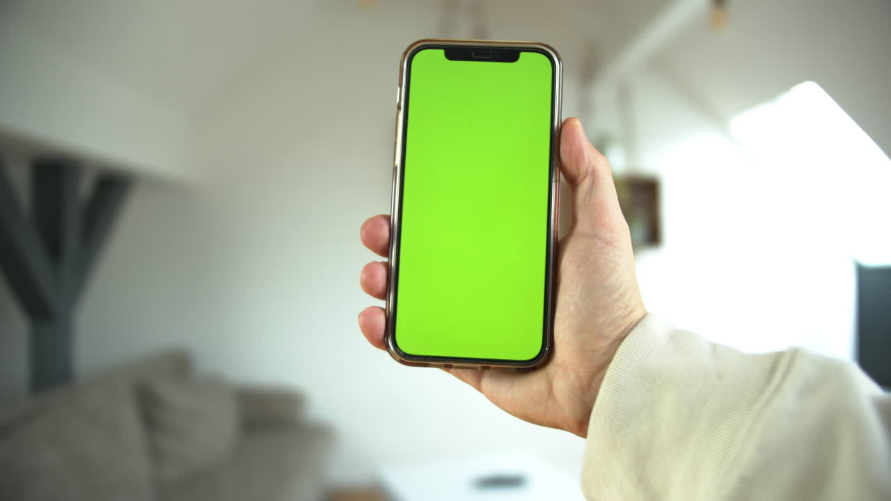 un punto de vista de un hombre sosteniendo un teléfono inteligente con pantalla verde en posición vertical en un fondo blanco aislado
