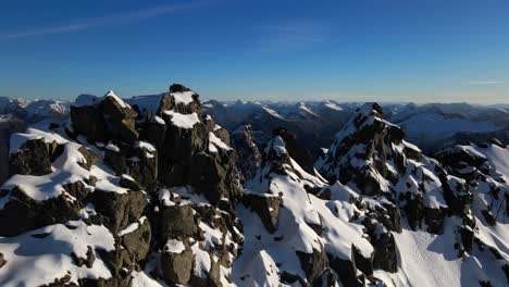 toma aérea en órbita que muestra rocas nevadas en la cima de la cordillera en noruega, jønshornet