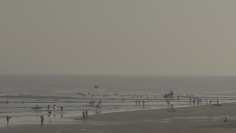 surfers at a beach with a hazy sky