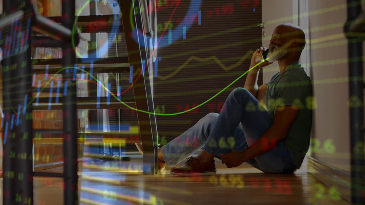 Animation of stock market data processing against african american man talking on smartphone at home