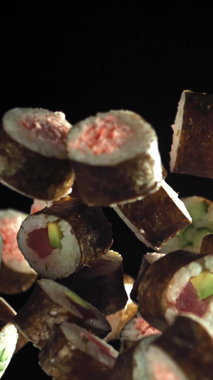 Deliziosi roll di sushi giapponese che fluttuano su sfondo nero
