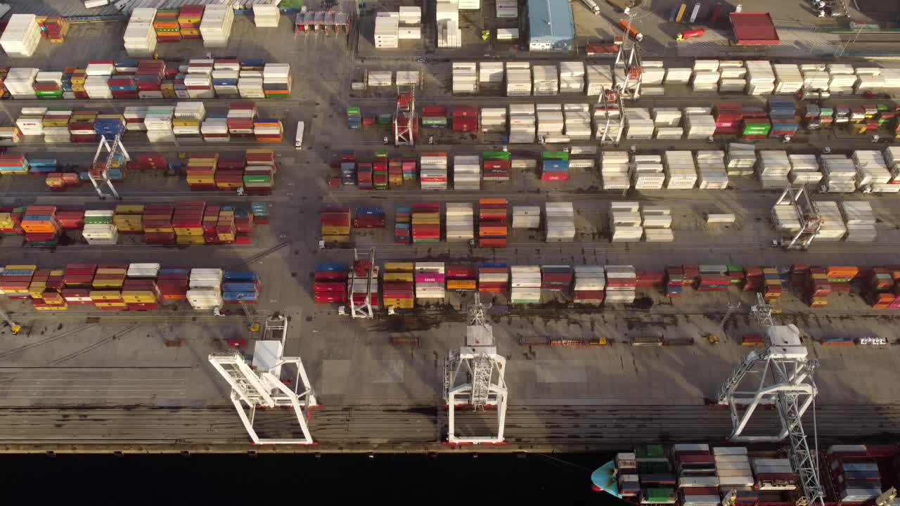 Port full of stacked shipping containers handled by cranes