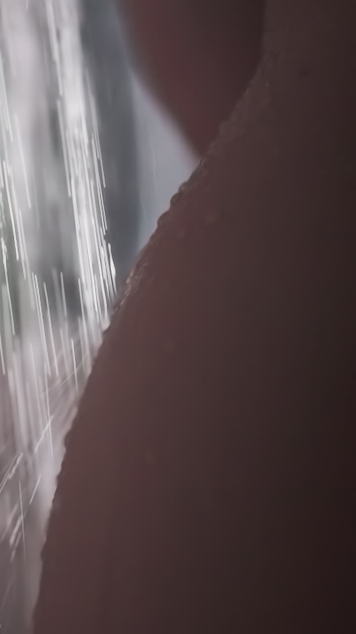 Naked body of woman under strong stream of water. Woman washes body under hot water in bathroom. Hip with waist of woman under warm stream of water