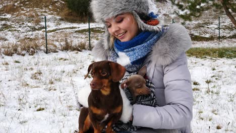 mujer jugando con sus perros pequeños fuera del invierno