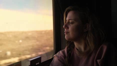 daydreaming on the train, blonde woman on train observes the sights passing by