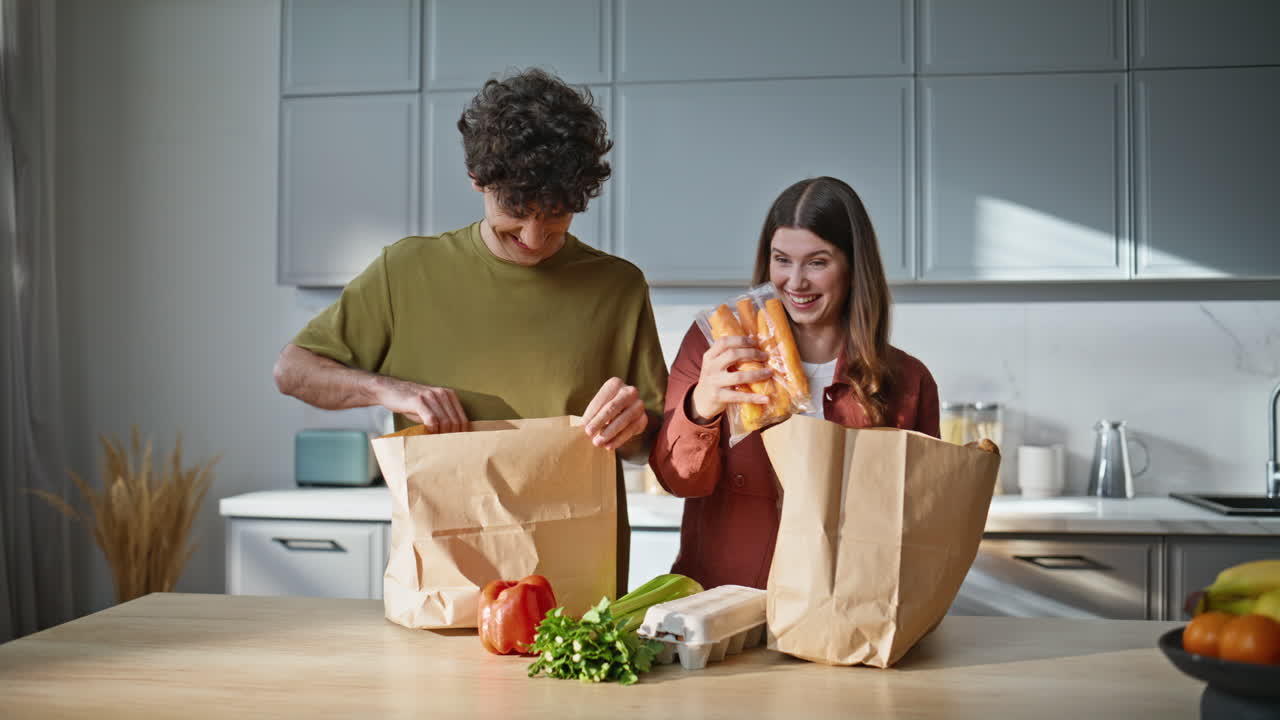Young pair unpacking products from store at kitchen closeup. Lovers having fun