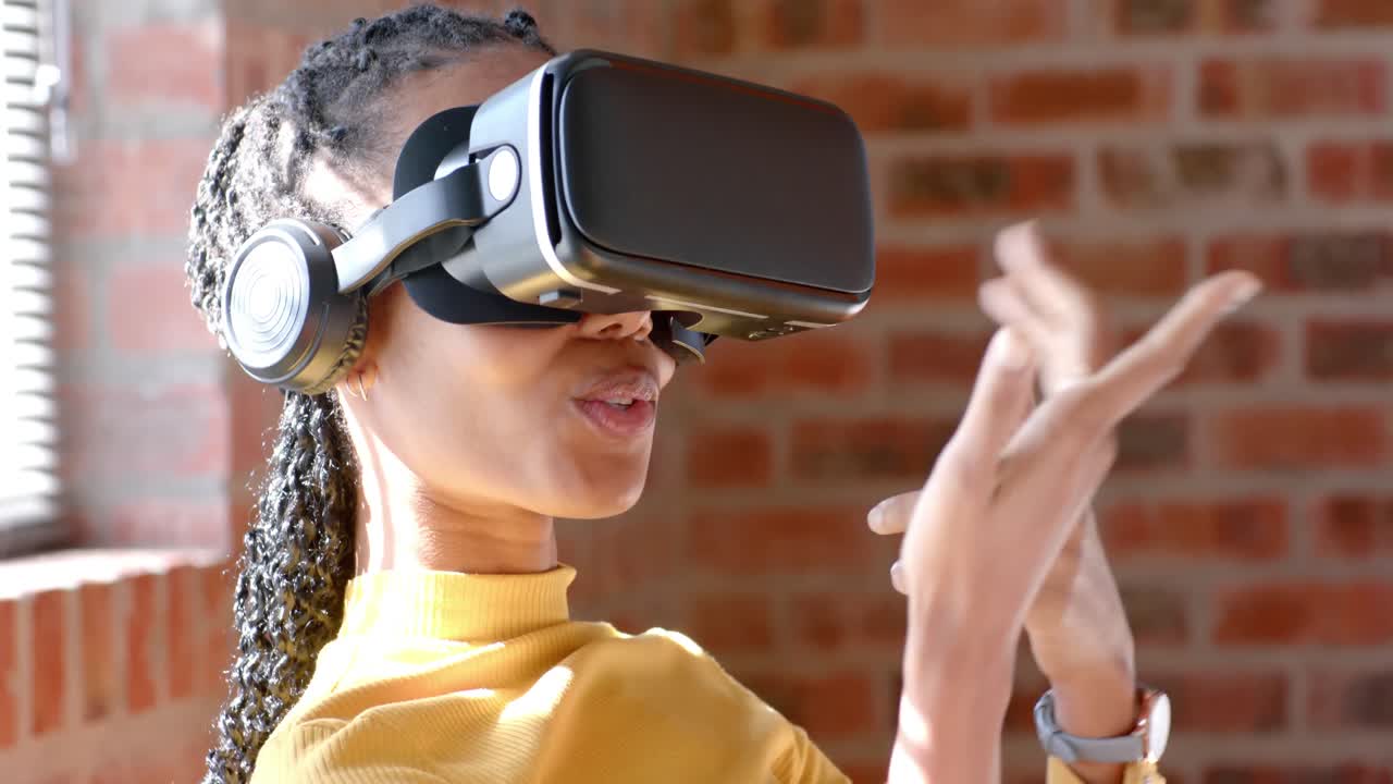 Glad afrikansk-amerikansk afslappet forretningskvinde bruger VR-headset og taler på kontoret, slow motion.
