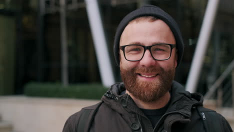 close-up portrait of a smiling bearded man in glasses and a beanie