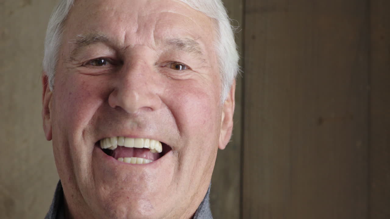 retrato en primer plano de un apuesto anciano sonriendo feliz disfrutando de un estilo de vida exitoso mirando a la cámara en un fondo de madera