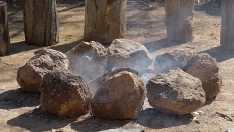 wooden logs burning on the campfire surrounded by rocks - outdoor camping - queensland, australia