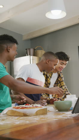 vertical video of happy diverse male teenage friends preparing pizza