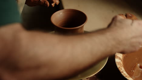 ceramist modeling clay jar in pottery. guy cleaning potters wheel with sponge