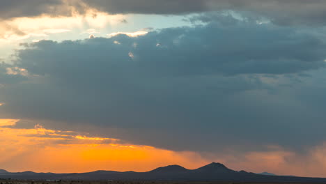 cloudscape colorido y dinámico con un chaparrón sobre una cordillera en silueta al amanecer - lapso de tiempo estático