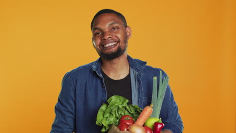 vegan adult presenting his ripe freshly harvested produce in a paper bag