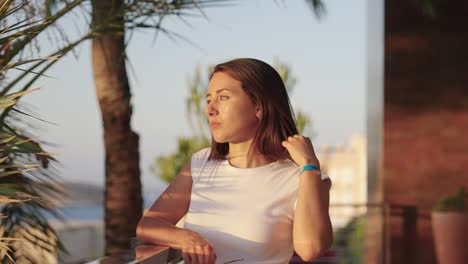 Attractive-female-brunette-touch-hair-at-beach-hotel-balcony,-Mallorca