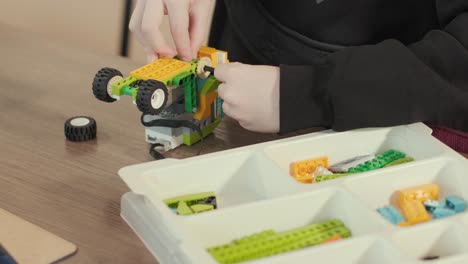 children intently focused on assembling parts from a robotics kit, with a tablet displaying instructions, promoting stem learning and creativity