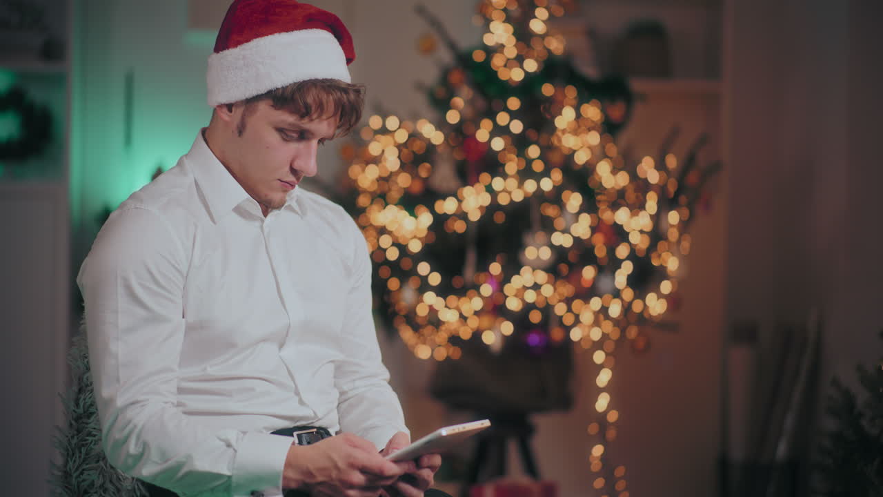 hombre usando una tableta digital mientras está sentado en una casa iluminada durante la navidad