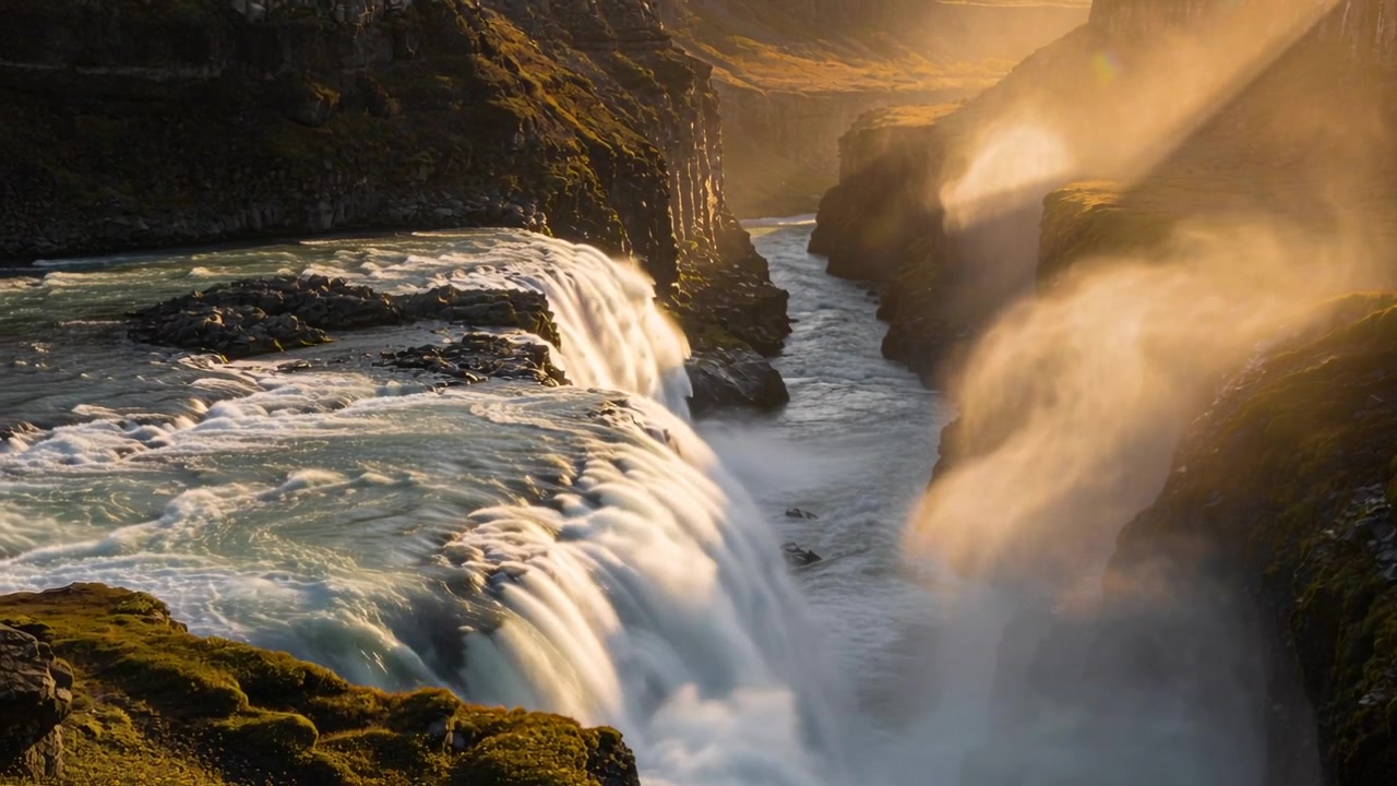 Fiume che scorre e raggiunge il bordo, gettandosi in una cascata di gola, formando una nebbia che proietta raggi su una sporgenza rocciosa coperta di muschio.
