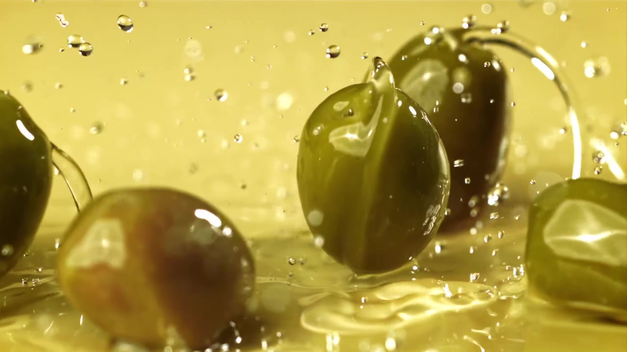 Olive che schizzano nell'olio d'oliva dorato al rallentatore