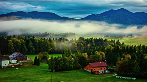 Timelapse-De-Niebla-Rodando-Sobre-Un-Vibrante-Paisaje-Otoñal-Con-Casas-Rústicas-Y-Colinas-Boscosas