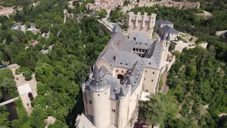 vista aérea del castillo de alcázar de segovia, inclinándose lentamente hacia arriba para revelar el paisaje de la ciudad en el fondo