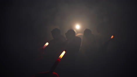 people silhouettes in smoky darkness with candles