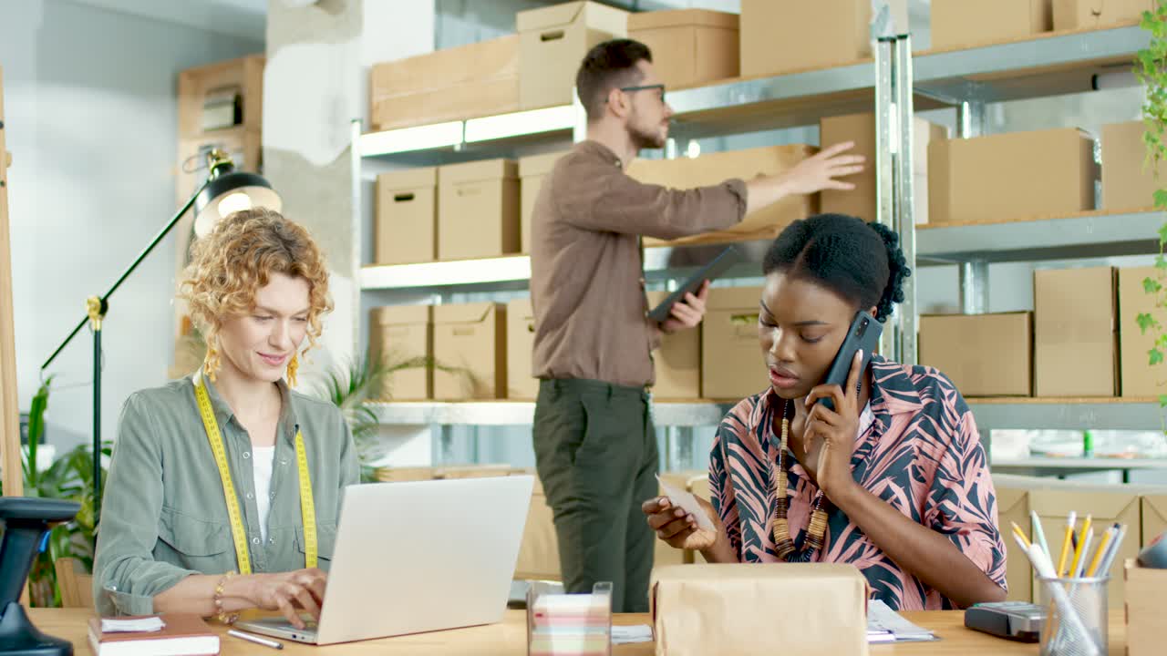 다민족 디자이너 팀 태블릿 입력, 노트북 검색, 패션 의류 매장에서 전화 통화